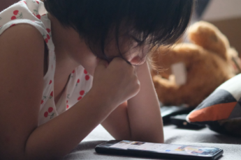 Little girl reading an ebook on a phone or tablet